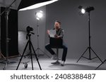 Casting call. Man with script sitting on chair and performing in front of camera in studio