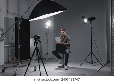 Casting call. Man with script sitting on chair and performing in front of camera in studio