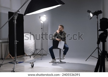 Casting call. Man with script sitting on chair against grey background in studio