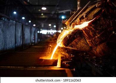 Casting, melting, molding and foundry. Bucket with hot molten iron pouring into the mold. Industrial steel production. - Powered by Shutterstock