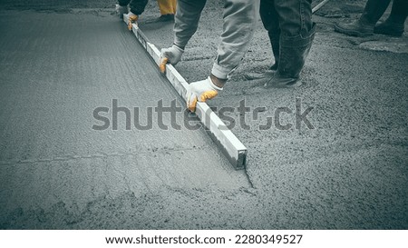 Cast-in-place work using trowels. Workers level cement mortar. Construction worker uses trowel to level cement mortar screed. Concrete works on construction site