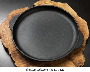 Cast-iron pan. On the table. On a wooden stand. Ribbed bottom.
