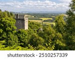 Castle Campbell in Dollar in the Scottish highlands, medieval fort with fortification and ruin in high mountains and forest in Scotland near Edinburgh with flag blowing in wind