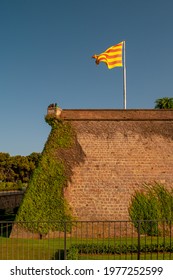 Montjuïc Castle With Catalan National Flag In Historical Downtown Of Barcelona, Spain, At Sunny Summer Day And Deep Blue Sky