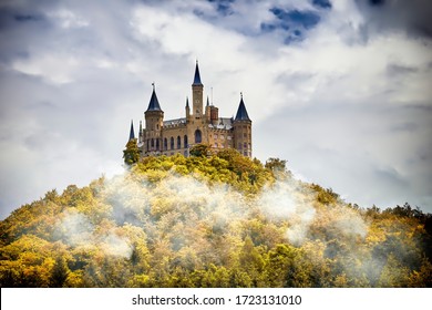 Castle on a wooded mountain in the fog under clouds, Hohenzollern, Germany