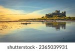 Castle reflected in wet sand at sunrise in northumberland
