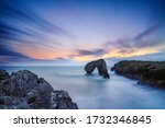 Castro de las Gaviotas at sunset. A rock formation that stands out of the sea. Long exposure shot to create the silky effect in the water.