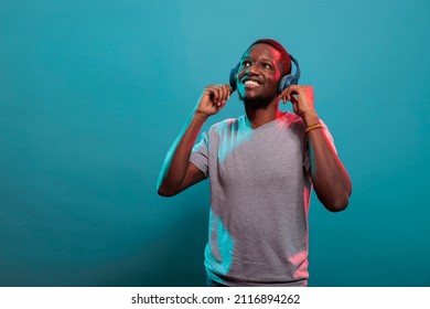 Casual adult listening to music on wireless headphones, enjoying audio sound and mp3 song on headset. Confident guy using earphones to enjoy stereo record and radio rhythm in studio.