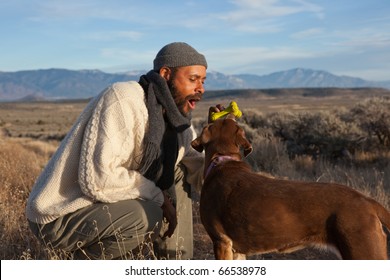 Casual African American Man Playing With And Talking To His Dog