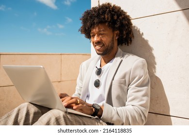 Casual African American man working in open air. Man in suit with beard using laptop. Sitting at terrace or rooftops. Working, manager, technology concept