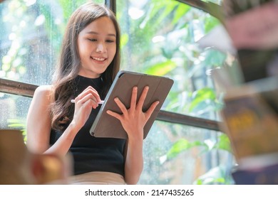 Casual Asia Female Woman Relax Hand Using Tablet Internet Surf Writing Diary Cheerful Smiling While Sittting In Warm Interior Of Cafe Near Big Window,asian Woman Sit On Stool Casual Work In Coffeeshop