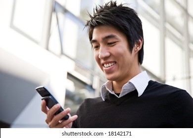 A Casual Asian Businessman Texting On His Cell Phone