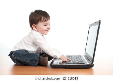 Casual baby smiling while is playing with a laptop computer in a white isolated background