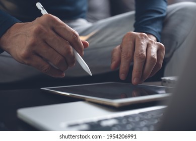 Casual Business Man With Stylus Pen Writing On Digital Notepad, Touching On Digital Tablet Screen, Working On Laptop Computer In Office. Graphic Designer Working His Project, Dark Tone, Close Up. 