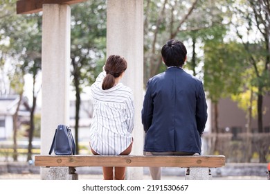 Casual Business Man And Woman Sitting On A Park Bench