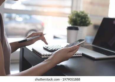 Casual Business Woman, Female Entrepreneur Using Calculator And Mobile Phone During Online Working On Laptop Computer On Office Table At Home, Telecommuting, Work From Home Concept