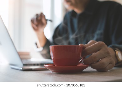 Casual Businessman, Freelancer Relaxed Working On Laptop Computer And Drinking Morning Coffee At Home Office. Man Browsing Internet Via Laptop Computer With Digital Tablet On Table In Coffee Shop.