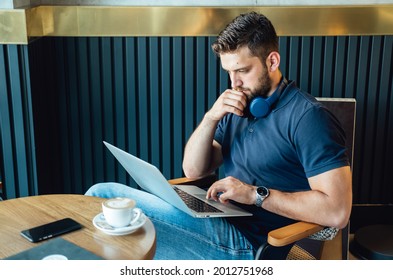Casual Businessman Working in a Cafe on his Laptop Computer.
Handsome business man reading business report on laptop computer while drinking coffee and sitting at table in a restaurant.