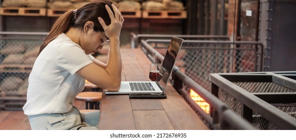 Casual Businesswoman Serious And Concerned With Laptop Computer, Asian Woman Stressed And Tired From Work In Workspace Or Cafe. Busy Business, Workload And Unhappy Concept