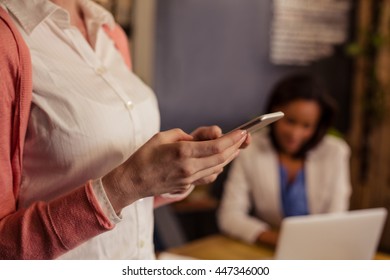 Gelegentliche Geschäftsfrau mit Smartphone im Büro