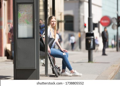 Casual caucasian teenager commuter with modern foldable urban electric scooter sitting on a bus stop bench waiting for metro city bus. Urban mobility concept. - Powered by Shutterstock