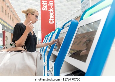 Casual caucasian woman using smart phone application and check-in machine at the airport getting the boarding pass. Modern technology on airport.