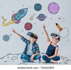 casual children using virtual reality headsets while sitting on the floor with doodle space pictures on walls - Powered by Shutterstock