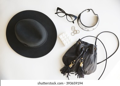 Casual day look. Outfit of young woman. Essentials for modern young lady. Different female accessories on white background: hat phone money glasses silver jewelry (rings) boho bag with tassels