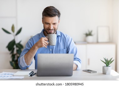 Casual Day In Office. Smiling Male Employee Using Laptop And Drinking Coffee At Workplace, Looking At Computer Screen, Free Space - Shutterstock ID 1805980945