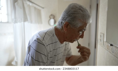 Casual Domestic Scene of Elderly Man Brushing Teeth as Part of Morning Routine. older person dental hygiene and washing face, starting the day ritual - Powered by Shutterstock