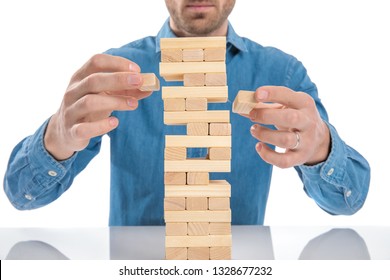 casual dressed man playing a game of jenga, just removed simultaneously two bricks at a time - Powered by Shutterstock