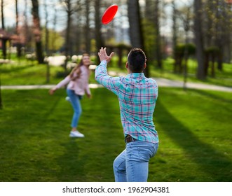 Casual dressed young couple playing freesbie in the park  - Powered by Shutterstock