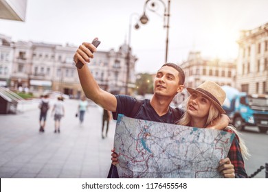 Casual embracing man woman taking selfie on street while exploring city with map during trip 