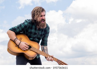 casual guy express human emotions while performance. hipster with long hair and moustache guitarist. male guitarist with musical instrument. country music concept. bearded man play acoustic guitar
