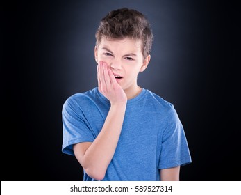 Casual Guy Have Toothache, On Black Background. Emotional Portrait Of Teen Boy - Sad Child With Tooth Pain. Dental Problem - Teenager Suffering From Toothache.