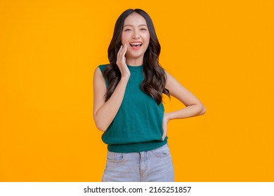 casual happiness asian female woman smiling cheerful in green tshirt blue jean relax peaceful positive thinking carefree lifestyle standing hand gesture face expression with yellow color background  - Powered by Shutterstock