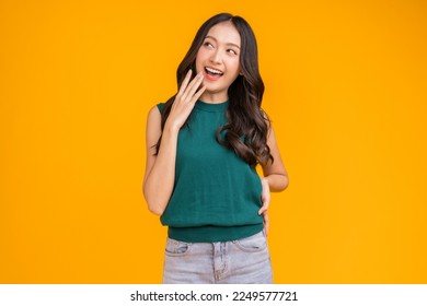 casual happiness asian female woman smiling cheerful in green tshirt blue jean relax peaceful positive thinking carefree lifestyle standing hand gesture face expression with yellow color background  - Powered by Shutterstock