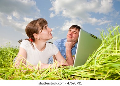 Casual happy couple on a laptop computer outdoors