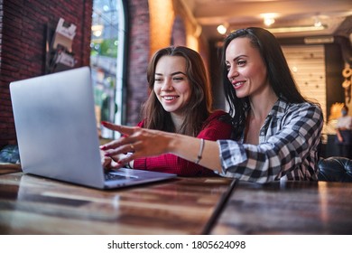 Casual happy smiling mother and daughter watching together video content on a laptop and having good time together in a coffee shop - Powered by Shutterstock