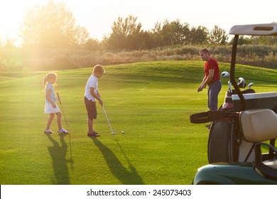 Casual kids at a golf field holding golf clubs studing with trainer. Sunset