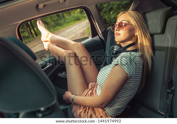 Casual look female  travel by car.She sitting\
on back seat relaxed and chills\
out.