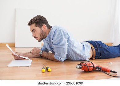 Casual Man Reading Instruction Manual For Power Tool At Home In The Living Room