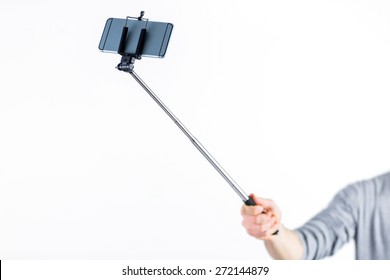 Casual man using a selfie stick shot in studio