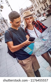 Casual Man And Woman Holding Paper Map And Exploring City While Standing On Street