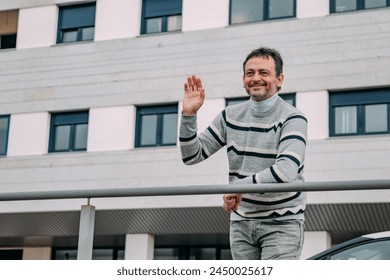 casual mature man leaning on street railing waving - Powered by Shutterstock