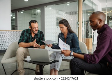 Casual meeting of smiling diverse business team analyzing financial data. Group team discussion in office lobby - Powered by Shutterstock