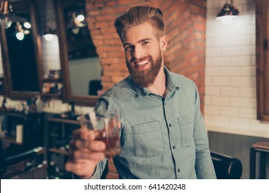 Casual Men`s Life. Cheers! Handsome Young Red Bearded Man In Casual Jeans Outfit, Drinking Whiskey At The Barber Shop, Enjoying And Smiling