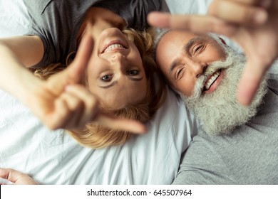 Casual Middle Aged Couple Lying In Bed And Smiling