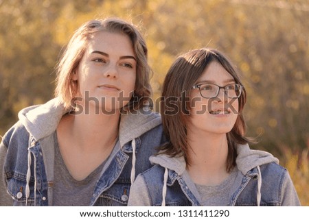 Casual outdoor portrait of two teen sisters with warm golden colors 