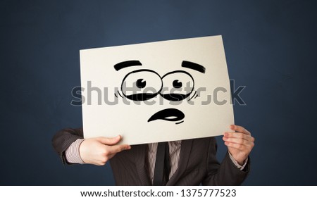 Casual person holding a paper with funny emoticon in front of her face
